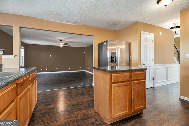 kitchen featuring stainless steel fridge, a textured ceiling, ceiling fan, dark hardwood / wood-style floors, and a kitchen island