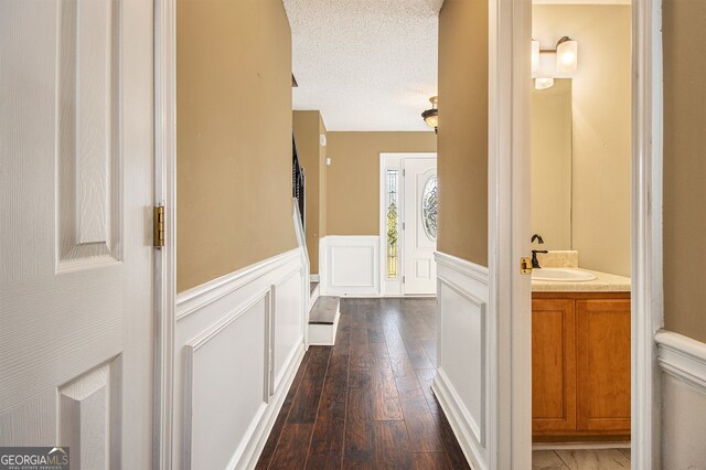 corridor featuring a textured ceiling, dark wood-type flooring, and sink