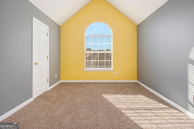 carpeted empty room featuring vaulted ceiling