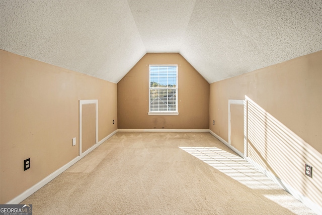 additional living space with a textured ceiling, light carpet, and lofted ceiling