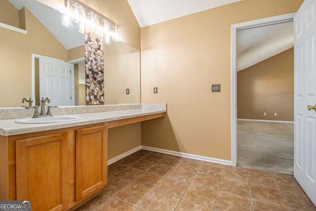 bathroom with tile patterned flooring, vanity, a textured ceiling, and vaulted ceiling