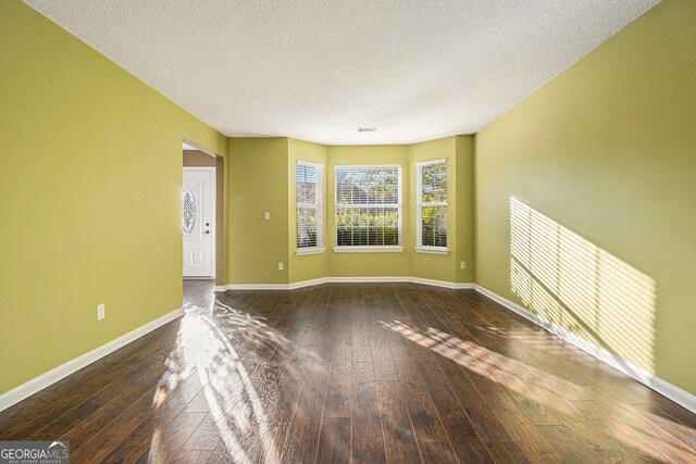 unfurnished room featuring a textured ceiling and dark wood-type flooring