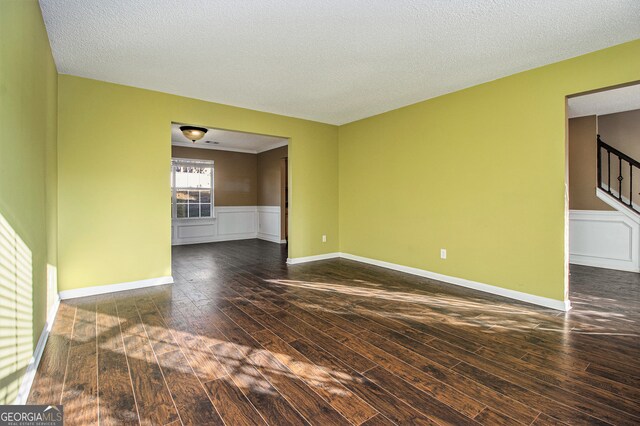 spare room featuring dark wood-type flooring and a textured ceiling