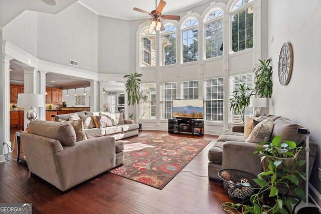 living room featuring a high ceiling, dark hardwood / wood-style flooring, ceiling fan, and ornamental molding