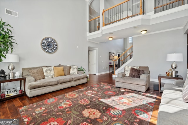 living room with crown molding, dark wood-type flooring, and a high ceiling