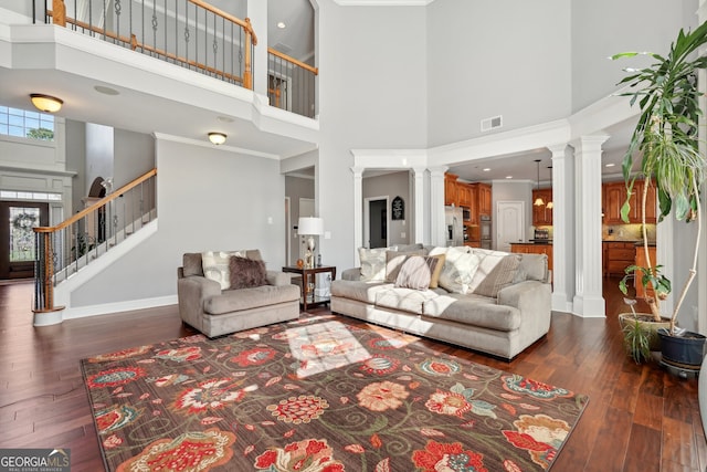 living room with crown molding, dark hardwood / wood-style flooring, and a towering ceiling