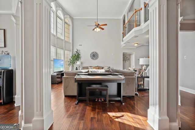 living room with ornate columns, dark wood-type flooring, a high ceiling, and ornamental molding