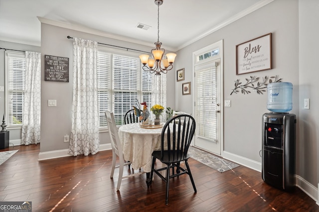 dining room with dark hardwood / wood-style floors, ornamental molding, and an inviting chandelier