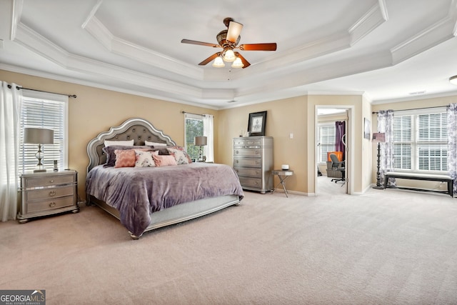 carpeted bedroom featuring ceiling fan, a raised ceiling, and multiple windows