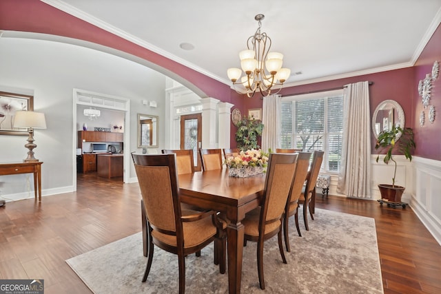 dining space featuring a chandelier, decorative columns, crown molding, and dark wood-type flooring