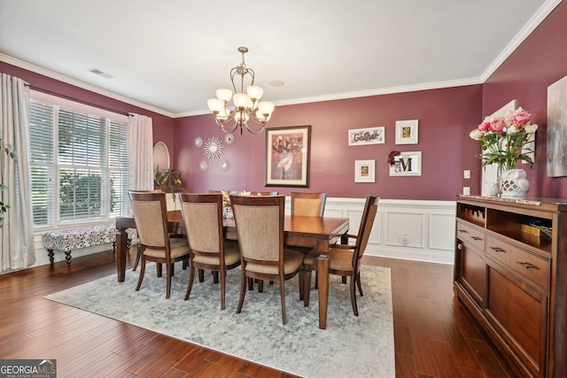 dining space with dark wood-type flooring, crown molding, and a notable chandelier