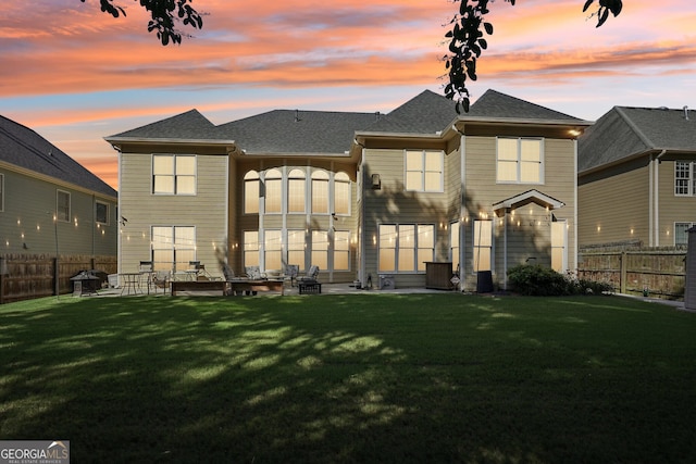 back house at dusk with a lawn and a patio