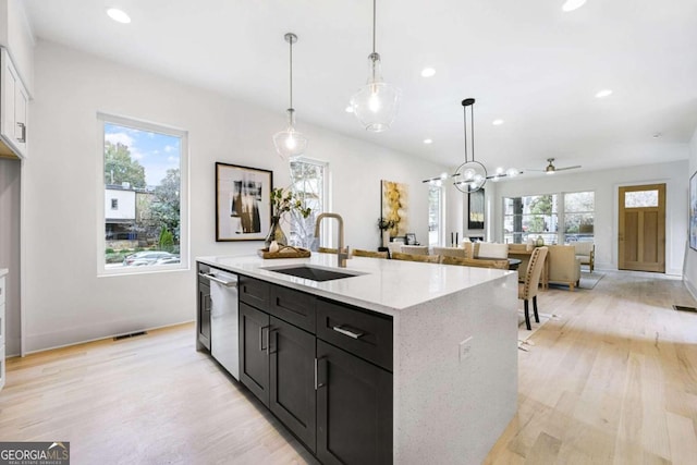 kitchen with light stone countertops, sink, pendant lighting, light hardwood / wood-style flooring, and dishwasher