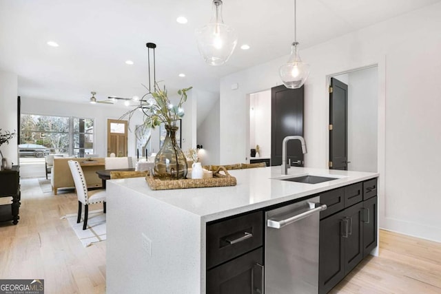 kitchen with a center island with sink, pendant lighting, light wood-type flooring, and sink