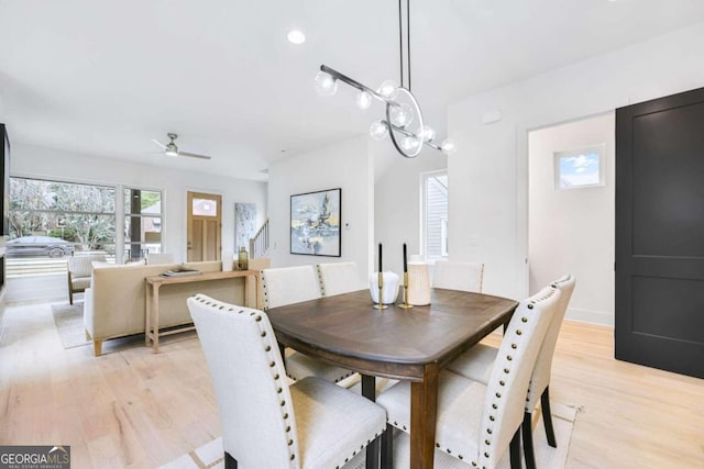 dining room with ceiling fan with notable chandelier and light wood-type flooring