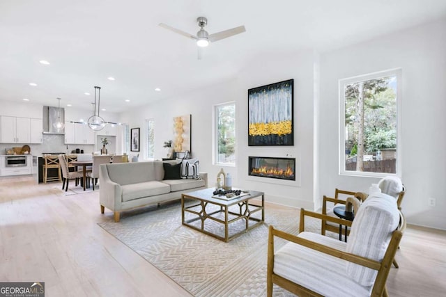 living room featuring plenty of natural light, light hardwood / wood-style floors, and ceiling fan