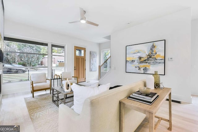 living room with ceiling fan, plenty of natural light, and light wood-type flooring