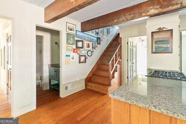 stairway with beamed ceiling and wood-type flooring