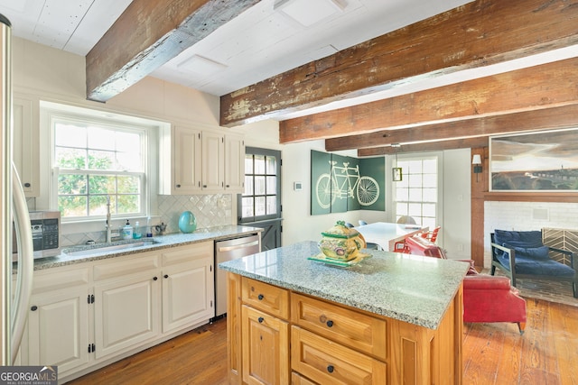 kitchen with dishwasher, sink, a healthy amount of sunlight, light hardwood / wood-style floors, and a kitchen island