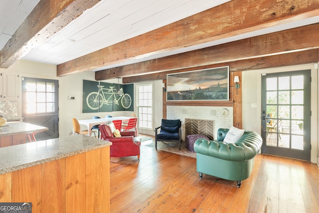 living room with beamed ceiling, light hardwood / wood-style floors, and a wealth of natural light