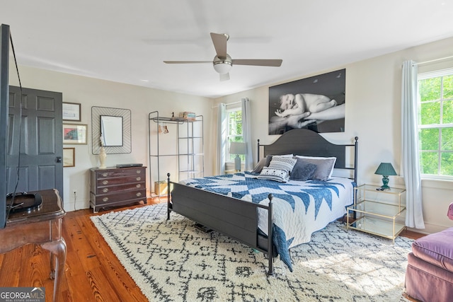 bedroom featuring wood-type flooring, multiple windows, and ceiling fan