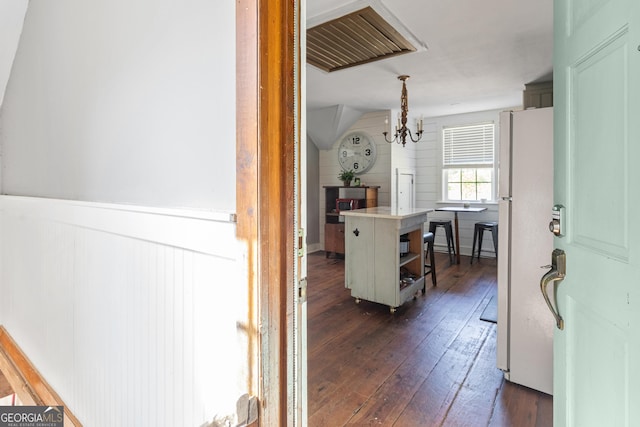 corridor featuring vaulted ceiling, dark hardwood / wood-style floors, and an inviting chandelier