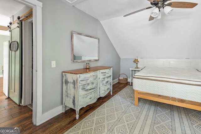 bedroom featuring ceiling fan, a barn door, wood-type flooring, and lofted ceiling