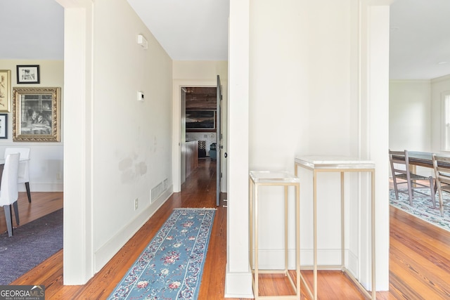 corridor with hardwood / wood-style floors and crown molding