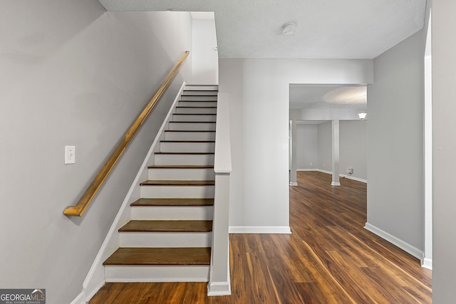 stairway with a textured ceiling and hardwood / wood-style flooring