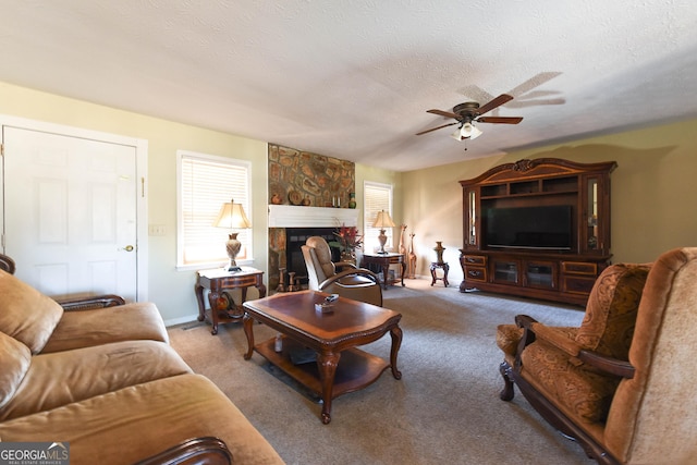 carpeted living area featuring a textured ceiling, a fireplace, a ceiling fan, and baseboards