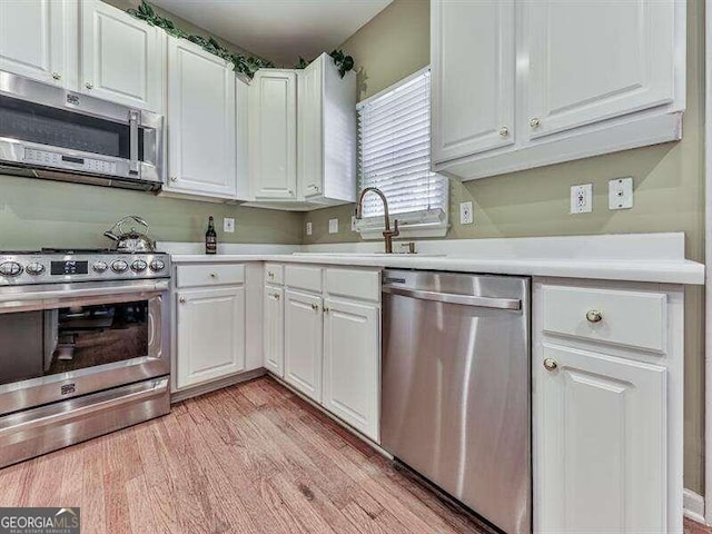 kitchen with white cabinets, light wood-type flooring, and appliances with stainless steel finishes