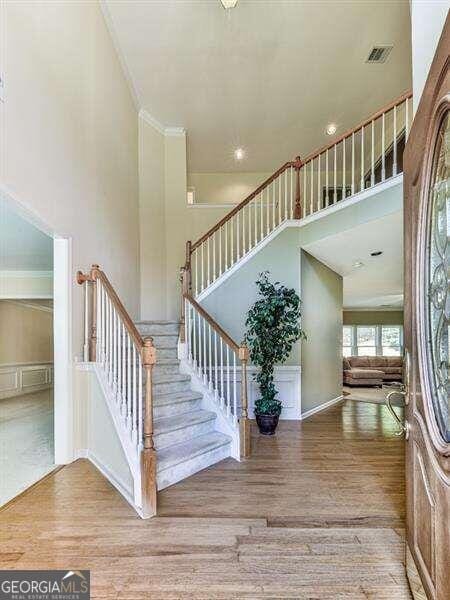 stairs featuring hardwood / wood-style floors, a high ceiling, and ornamental molding