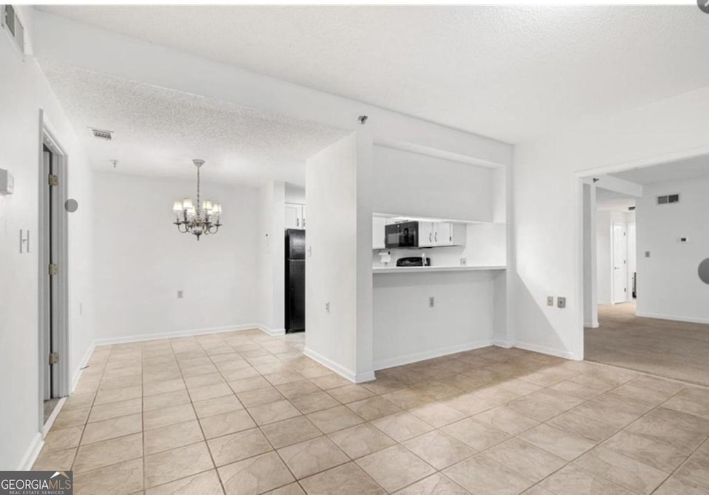 kitchen with a textured ceiling, black appliances, decorative light fixtures, an inviting chandelier, and white cabinetry