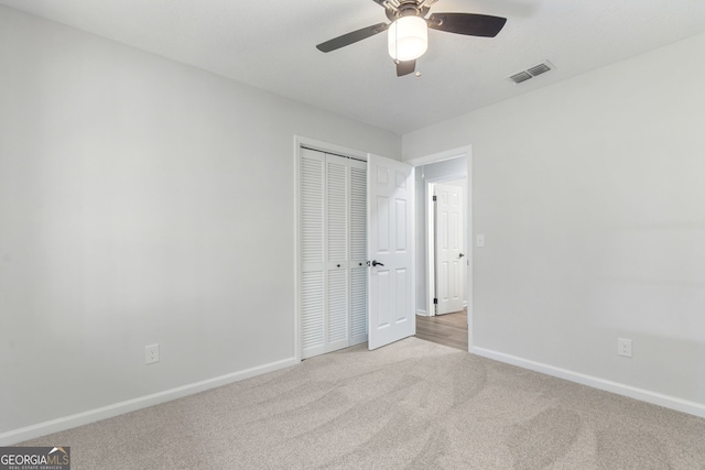 unfurnished bedroom with ceiling fan, a closet, and light colored carpet