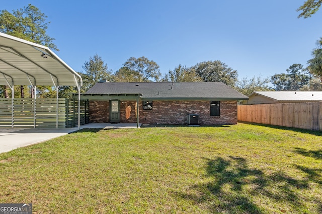 back of property with central air condition unit, a carport, and a lawn