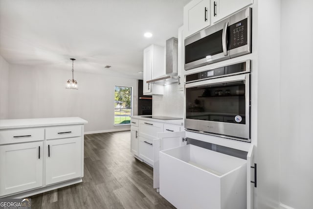 kitchen with decorative backsplash, appliances with stainless steel finishes, white cabinetry, and wall chimney range hood