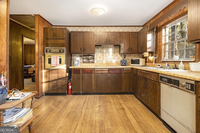 kitchen featuring decorative backsplash, dark brown cabinets, white appliances, sink, and light hardwood / wood-style flooring