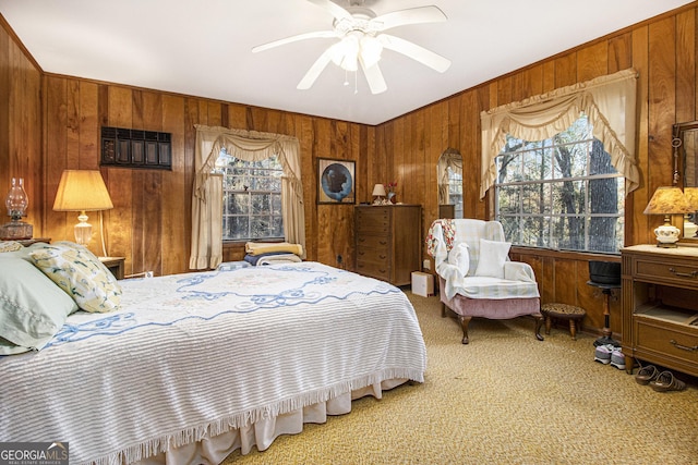 bedroom with ceiling fan, wood walls, and carpet floors