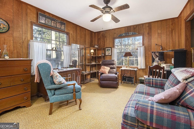 living area with light colored carpet, ceiling fan, and wood walls