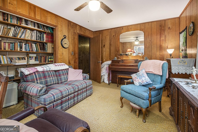 carpeted living room featuring wood walls and ceiling fan