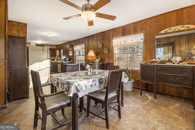 dining room with ceiling fan and wood walls