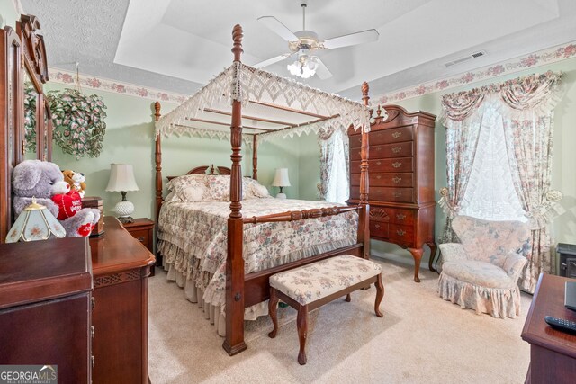 carpeted bedroom with ceiling fan and a raised ceiling