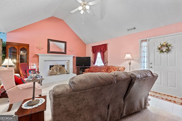 tiled living room with ceiling fan, a fireplace, and vaulted ceiling