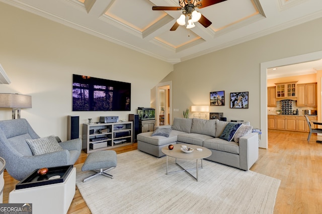 living room with light wood-type flooring, ceiling fan, crown molding, and coffered ceiling