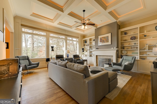 living room with coffered ceiling, crown molding, light hardwood / wood-style flooring, ceiling fan, and beam ceiling