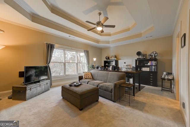 living room with ceiling fan, ornamental molding, light carpet, and a tray ceiling