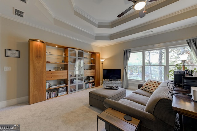 living room with ceiling fan, a raised ceiling, carpet floors, and ornamental molding