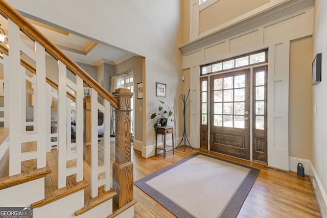 entrance foyer with wood-type flooring, crown molding, and a towering ceiling