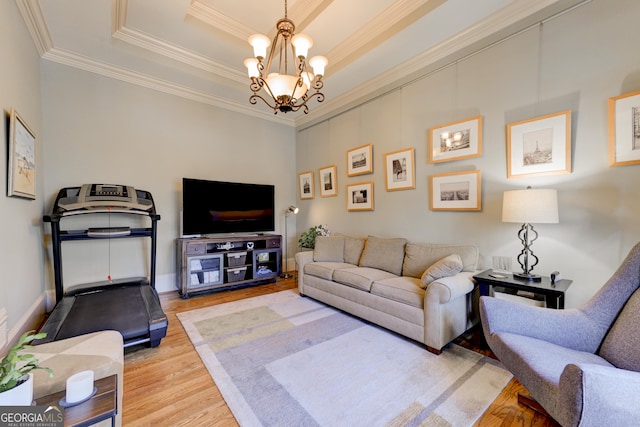 living room featuring a notable chandelier, a raised ceiling, crown molding, and light hardwood / wood-style flooring