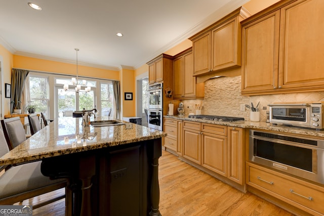 kitchen with stainless steel appliances, a center island with sink, a notable chandelier, and a breakfast bar area